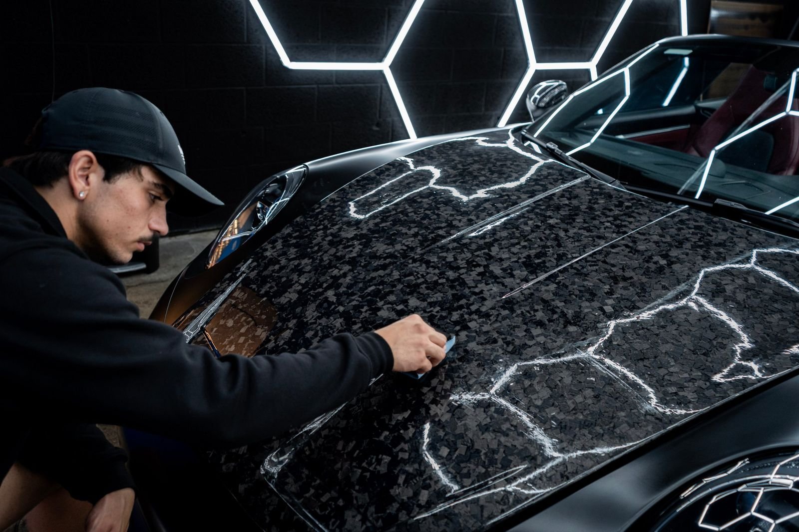 AquaBright detailer applying ceramic coating to a forged carbon Porsche hood